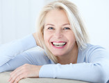 Active beautiful middle-aged woman smiling friendly and looking in camera. Woman’s face closeup. Realistic images without retouching with their own imperfections. Selective focus.