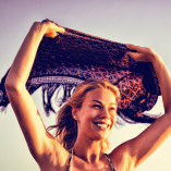 Happy woman holding scarf against clear sky
