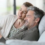 Mature couple using digital tablet relaxing in sofa