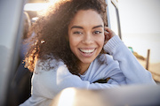Young woman leaning on open window of car looking to camera